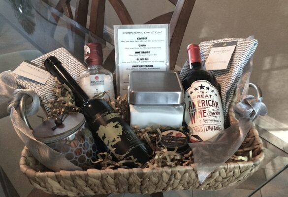 Woven basket filled with wine, pantry items, candle, and packaged foods