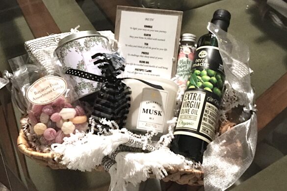 Gift basket with bottle of wine, glass jar candle, and packaged confections