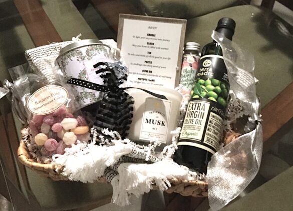 Gift basket with bottle of wine, glass jar candle, and packaged confections