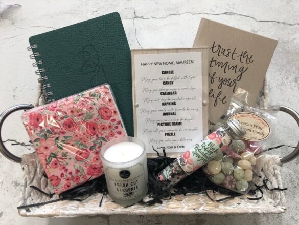 Gift basket with notebook, floral-patterned paper goods, candle, and wrapped sweets