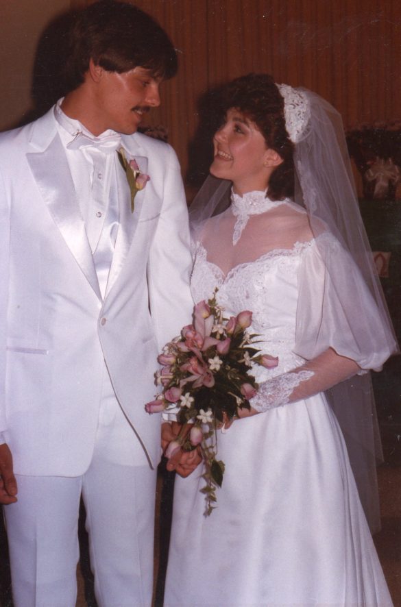 A couple all in white look at each on the alter of their wedding