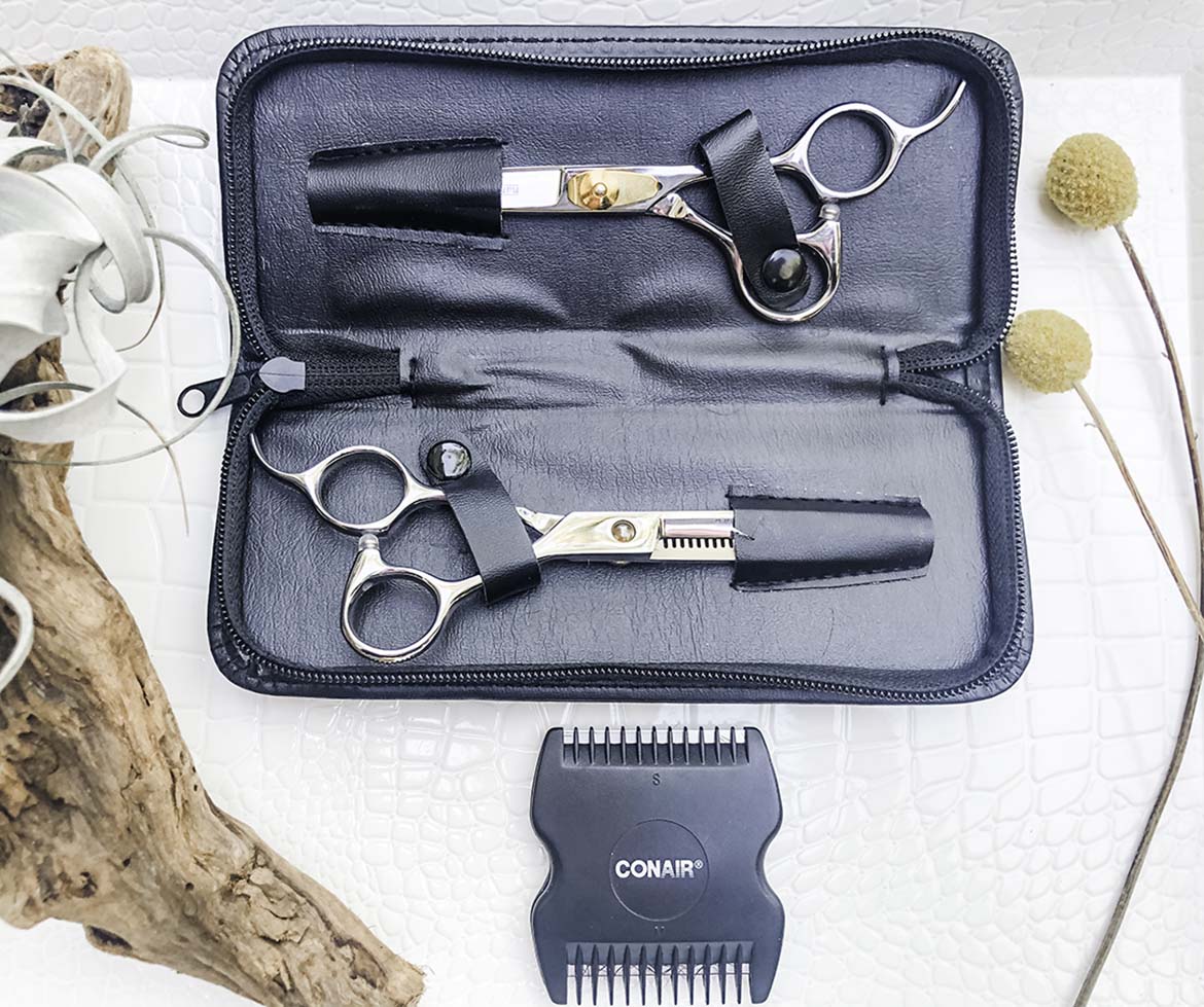 Professional hair scissors, thinning scissors, and a hair shape tool displayed on a tray.
