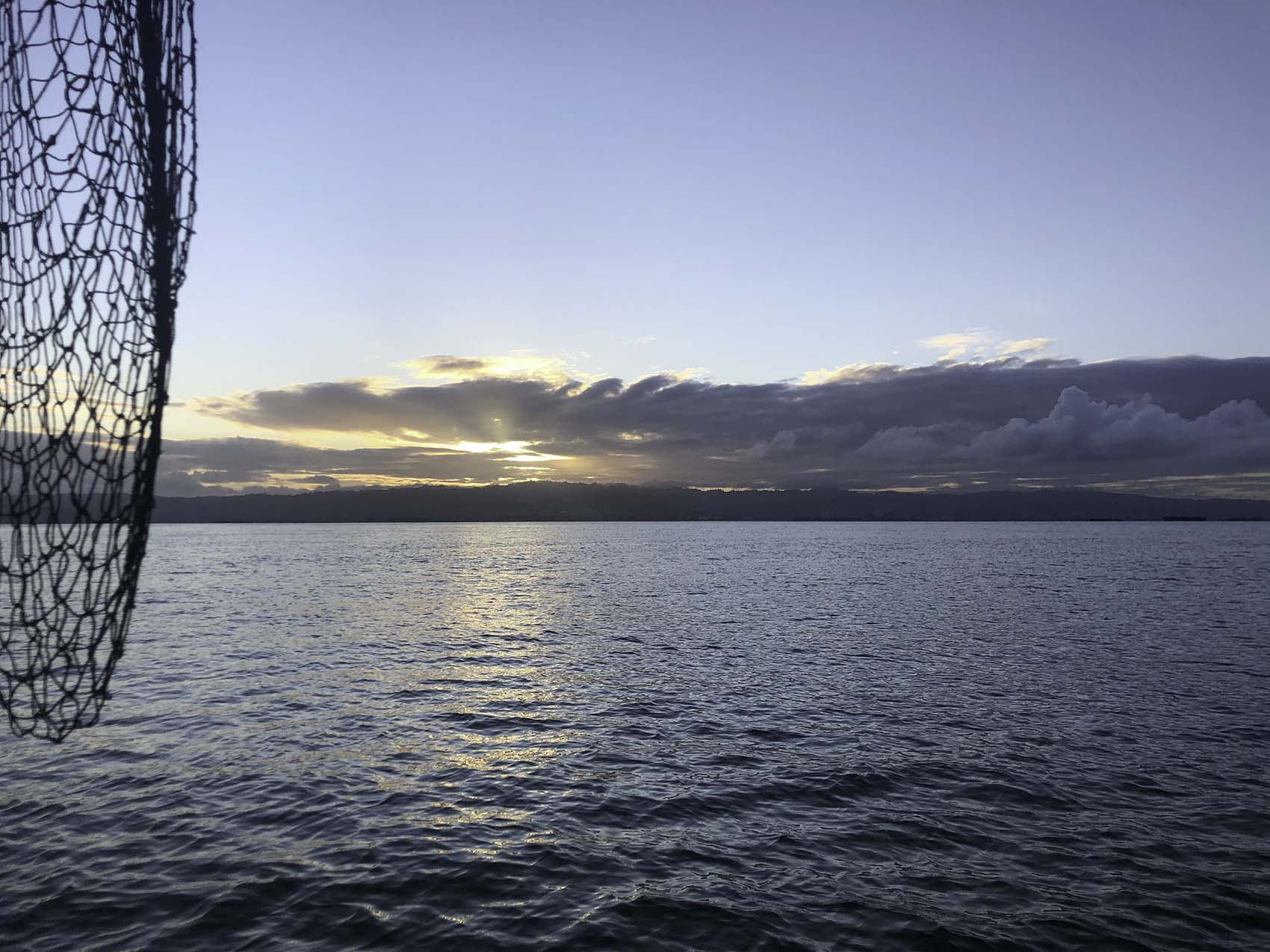 An image of San Francisco Bay at sunrise with a fishing net hanging off our boat