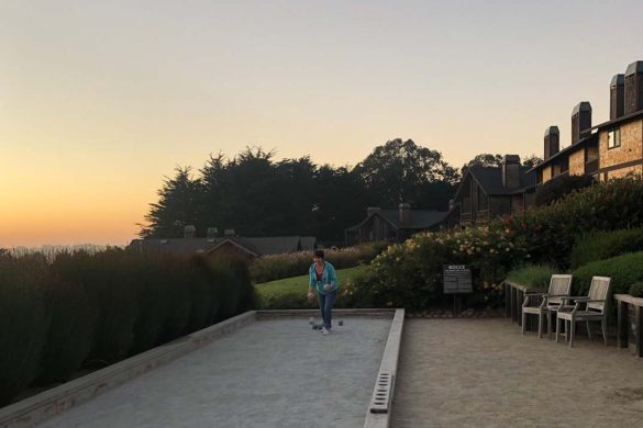 A woman plays bocce ball with a glorious sunset behind her