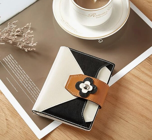 Stylish RFID wallet with black, white, and tan design on a table next to a cup of coffee