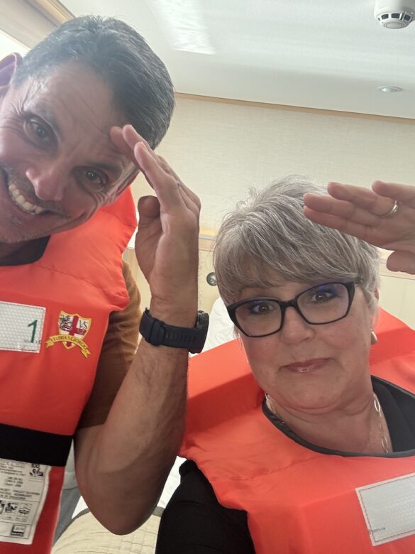 A couple wearing life jackets playfully salute the captain during a training drill in their room aboard a Viking River Cruise in Switzerland, 2024