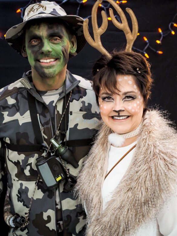 A mand dressed as a hunter in green camoflauge and woman dressed as a deer at a halloween party in 2019
