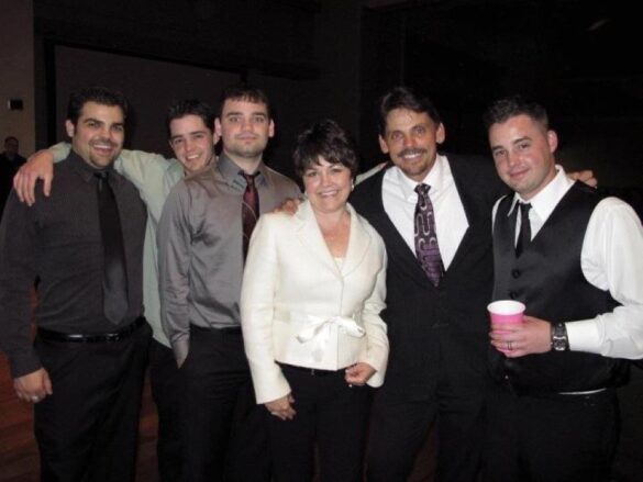 A happy couple dressed up and their four boys at a celebration.