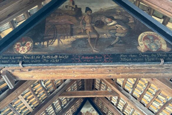 Historic triangular paintings inside Lucerne’s Chapel Bridge, including a skeleton leading a man away in a medieval Dance of Death scene