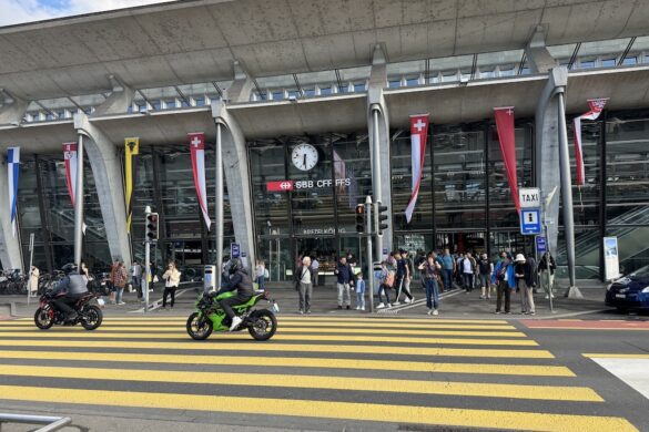 Lucerne train station exterior with crowds and yellow crosswalks, a transportation hub in Switzerland.