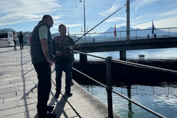 Man standing on Lucerne bridge with sun flare and mountains in the background