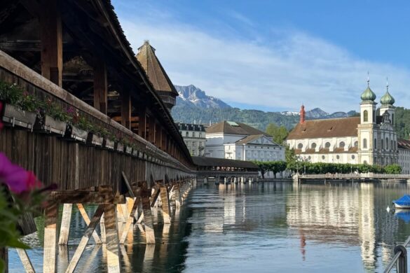Chapel Bridge crossing the Reuss River with the Jesuit Church and mountains in the background
