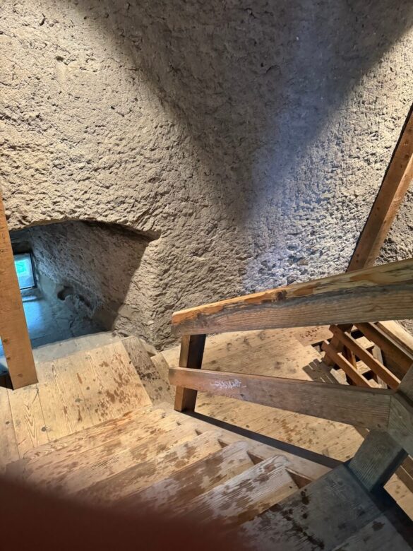 Steep wooden stairs and stone walls inside Musegg Tower, Lucerne.