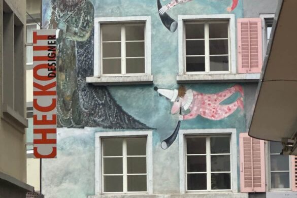 Colorful mural of masked carnival figures on Restaurant Fritschi in Lucerne