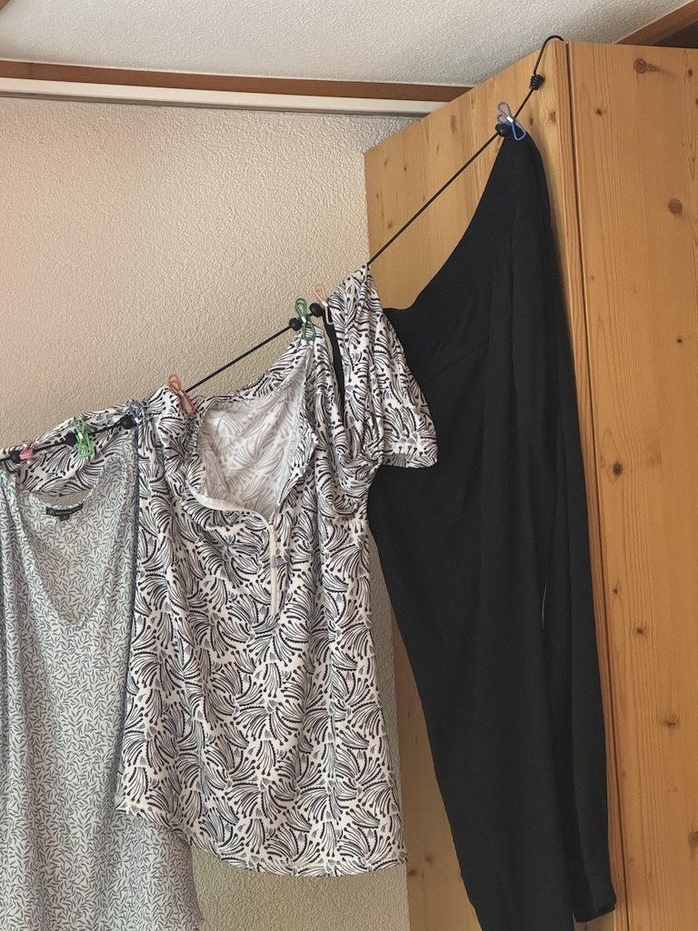 Colorful Hegs Pegs with hooks displayed in front of the product box, featuring pink, blue, and orange clips designed for hanging clothes without leaving crease marks.