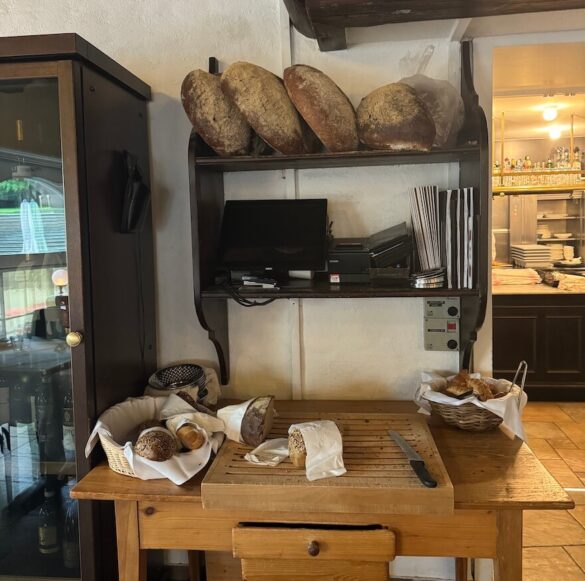 Bread station with whole loaves, a knife, and baskets of rolls in the breakfast room at Hotel Rebstock, Lucerne.