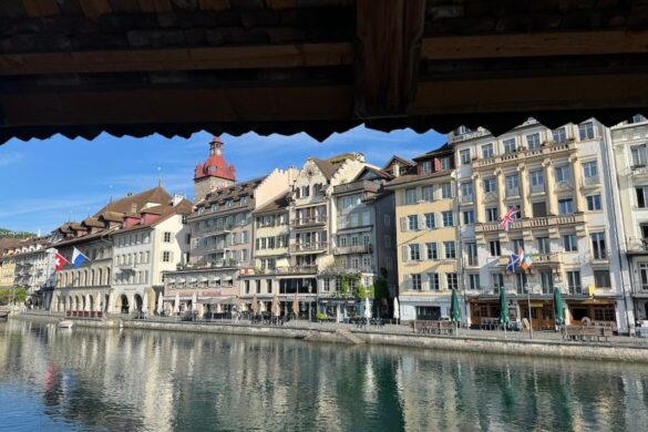 View of Lucerne’s riverside buildings through Chapel Bridge beams