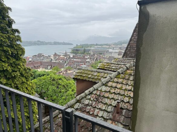 Moss-covered rooftops in Lucerne with a view toward Lake Lucerne and the Reuss River on a rainy day.