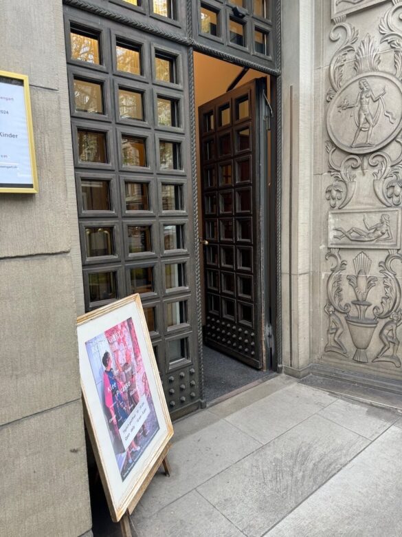 Open wooden double doors and stone carved exterior wall at the entrance of the Rosengart Museum, Lucerne, with an easel sign outside.