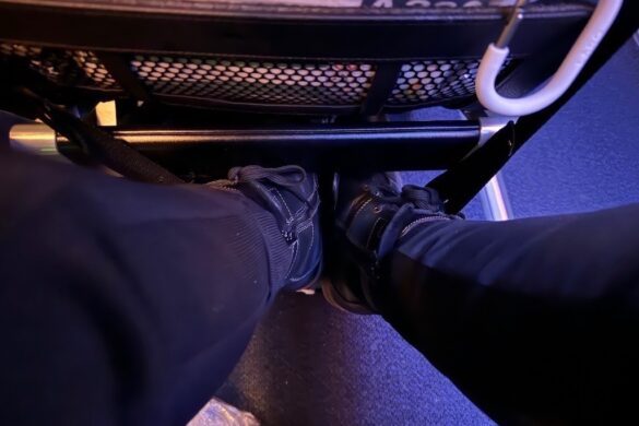 Legs resting in an airplane foot hammock during an international flight, part of 33 Days in Europe