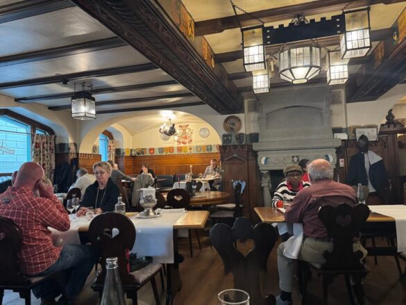 Interior view of the traditional dining room with a large stone hearth and wooden paneling at Restaurant Sauvage in Lucerne.