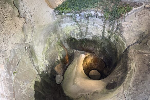 Close-up of a deep glacial pothole carved into rock at Glacier Gardens, Lucerne.