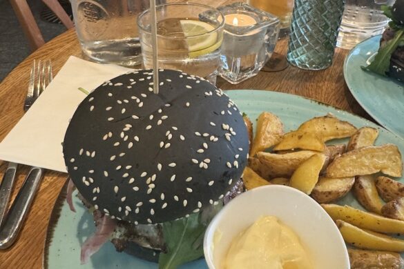 Black sesame burger with potato wedges and aioli on turquoise plate at Wirtshaus Krienbrüggli