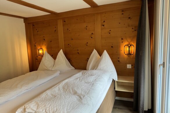Hotel Silberhorn room with two twin mattresses placed side by side under a wooden headboard with warm bedside lamps