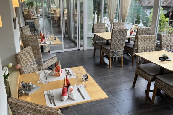 Restaurant with wicker chairs, wooden tables, and large windows at Hotel Silberhorn in Lauterbrunnen, Switzerland
