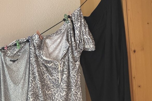 Portable laundry line with moveable clips holding shirts and pants, strung across a wooden wardrobe in a Lauterbrunnen hotel room