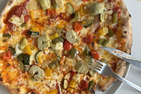 Freshly baked vegetable pizza with mushrooms, zucchini, and peppers served at a Lucerne restaurant table