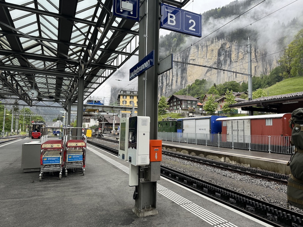 Red and yellow train at the Lauterbrunnen station platform with mountains and mist in the background on a rainy morning in Switzerland