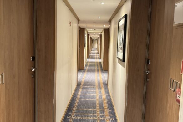 Hallway on the Viking Alruna with light wood doors and blue carpet leading to passenger staterooms
