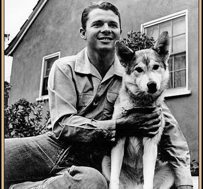 Audie Murphy smiling while sitting outdoors with his dog.