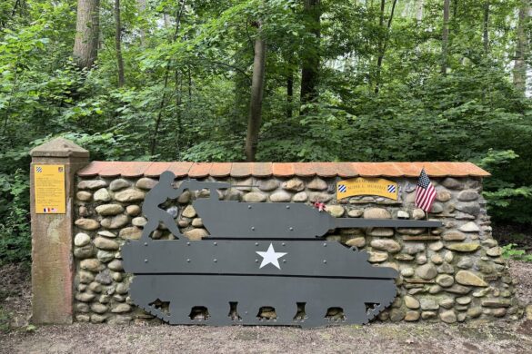 Stone wall featuring a tank silhouette with American and French flags at the Audie Murphy Memorial.
