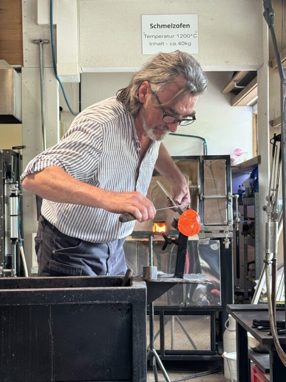 Glassblower shaping molten glass in a workshop at the Black Forest.