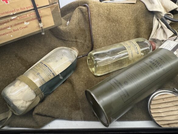 Museum display with glass bottles labeled distilled water and human plasma from World War II.