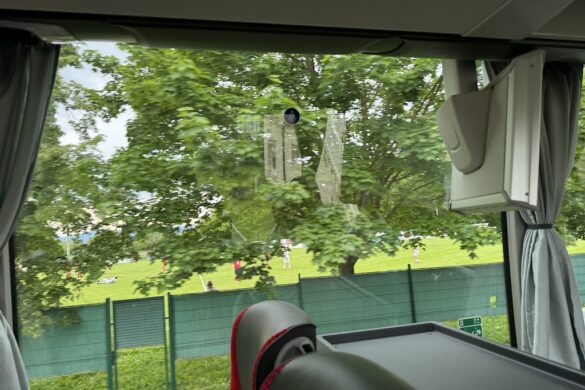 View of a school sports field with green grass and trees near the Audie Murphy Memorial in Holtzwihr, France.