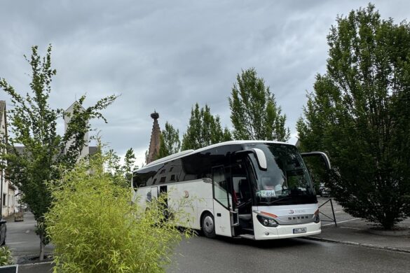Viking River Cruises tour bus parked on a village street surrounded by greenery.