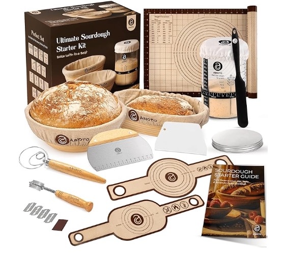 Sourdough starter kit with banneton baskets, bread lame, scoring tools, dough whisk, jars, and baked sourdough loaves arranged on a neutral surface
