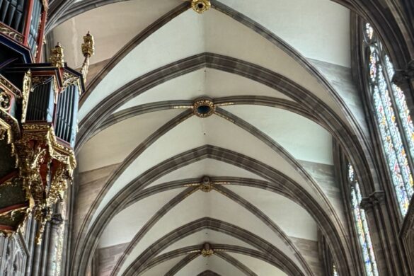 Looking up at a vaulted ceiling with ribbed arches inside Strasbourg Cathedral