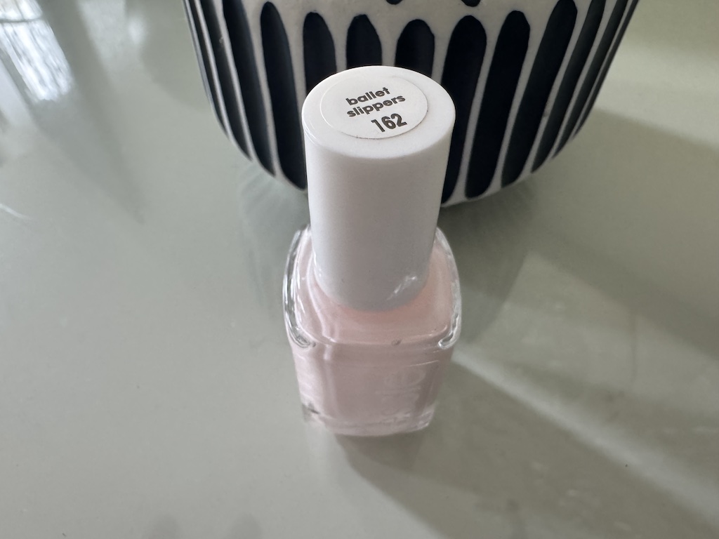 Pale pink Essie Ballet Slippers nail polish bottle on a light surface