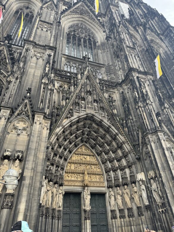Cologne Cathedral main portal with Gothic arches, sculpted saints, and gilded relief above the doors