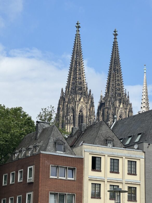 Cologne Cathedral twin Gothic spires rising above modern rooftops in the city