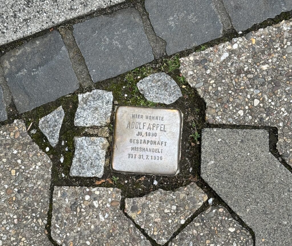 Stolperstein embedded in a cobblestone sidewalk engraved with the name Adolf Appel and details of his imprisonment and death.