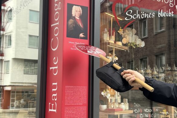 Viking River Cruise guide pointing with a paddle toward the portrait of Johann Maria Farina outside the Original Eau de Cologne shop in Cologne, Germany