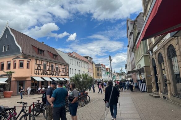 pedestrian shopping street with pastel and half timbered buildings bicycles and people walking under a blue sky with clouds