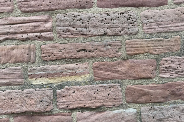 close up of red sandstone bricks with small pits holes and rough weathered surface texture