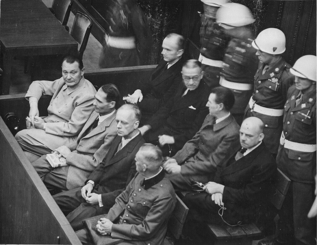 Hermann Göring seated at far left with other high-ranking Nazi officials in the dock during the Nuremberg trials courtroom proceedings