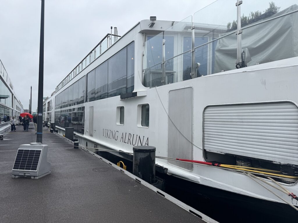 viking alruna river cruise ship docked in amsterdam on a rainy morning with passengers walking along the pier
